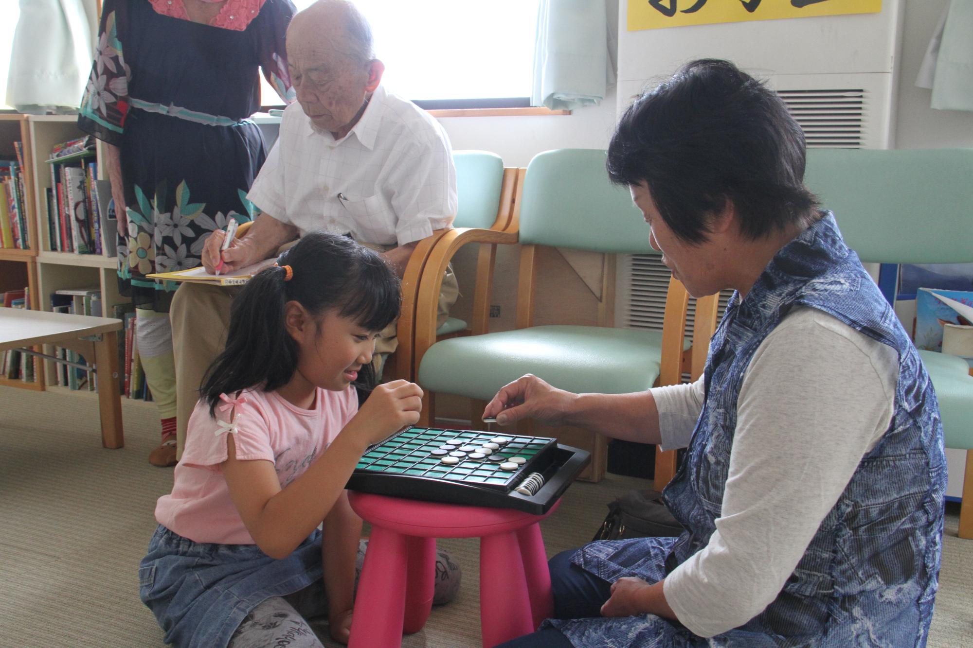 地域の高齢者とオセロを楽しむ子どもの様子