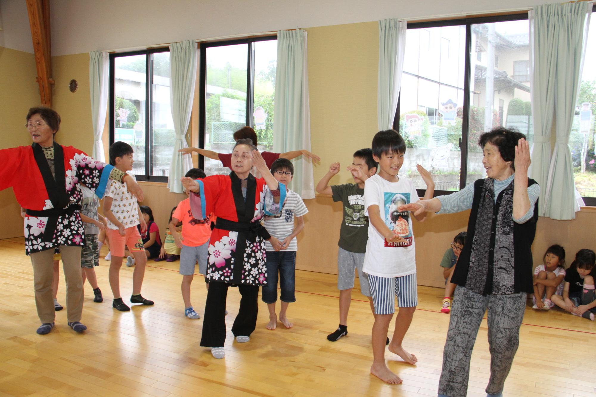 地域の高齢者から盆踊りを教わる子どもたちの様子