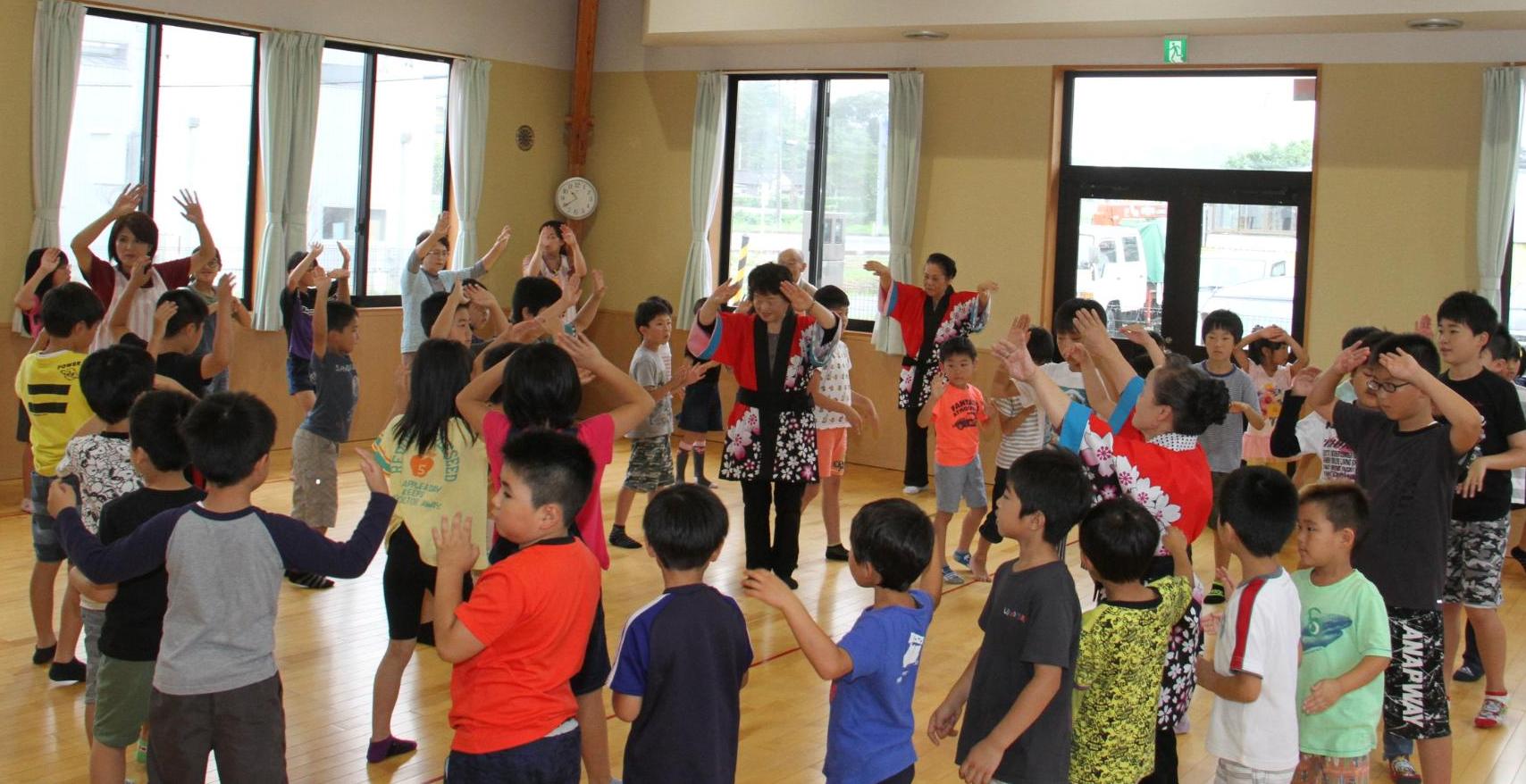 地域の高齢者といっしょに盆踊りを踊る子どもの様子