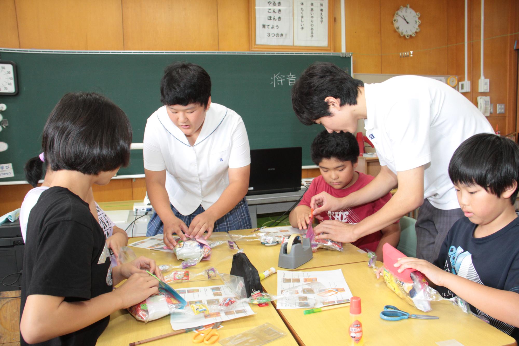 防災ポシェットを作成する児童とそれを手伝う淡路高校生との様子