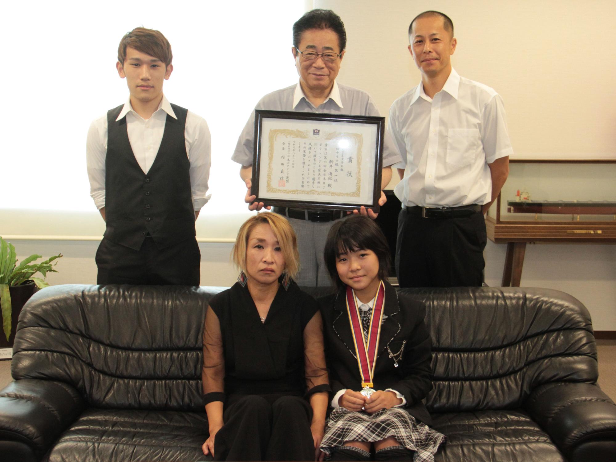 全日本大会での優勝を報告に来た新井さんらと市長が写真を撮る様子