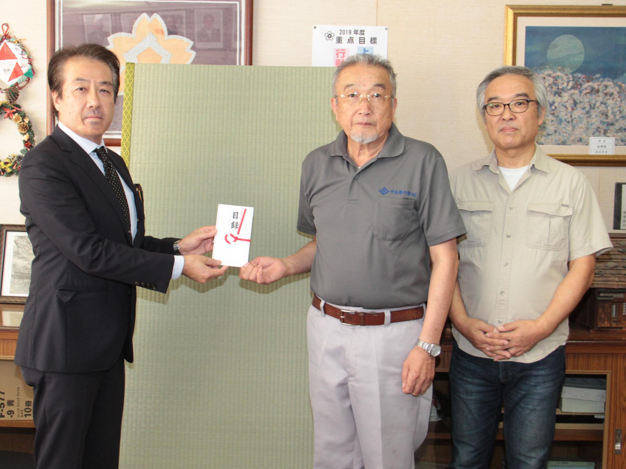 中島三喜県畳工業組合理事長と伏見健司有限会社フシミ代表取締役が畳を寄贈する様子