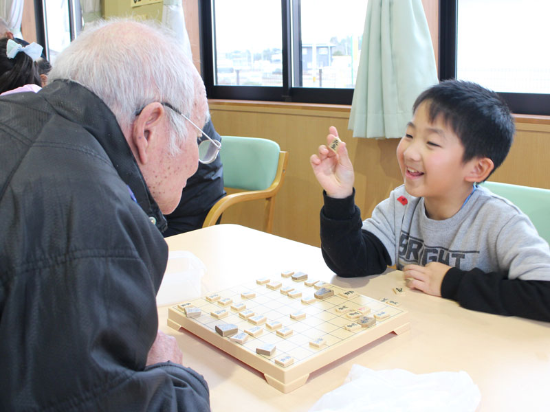 高齢者と将棋を楽しむ子どもの様子