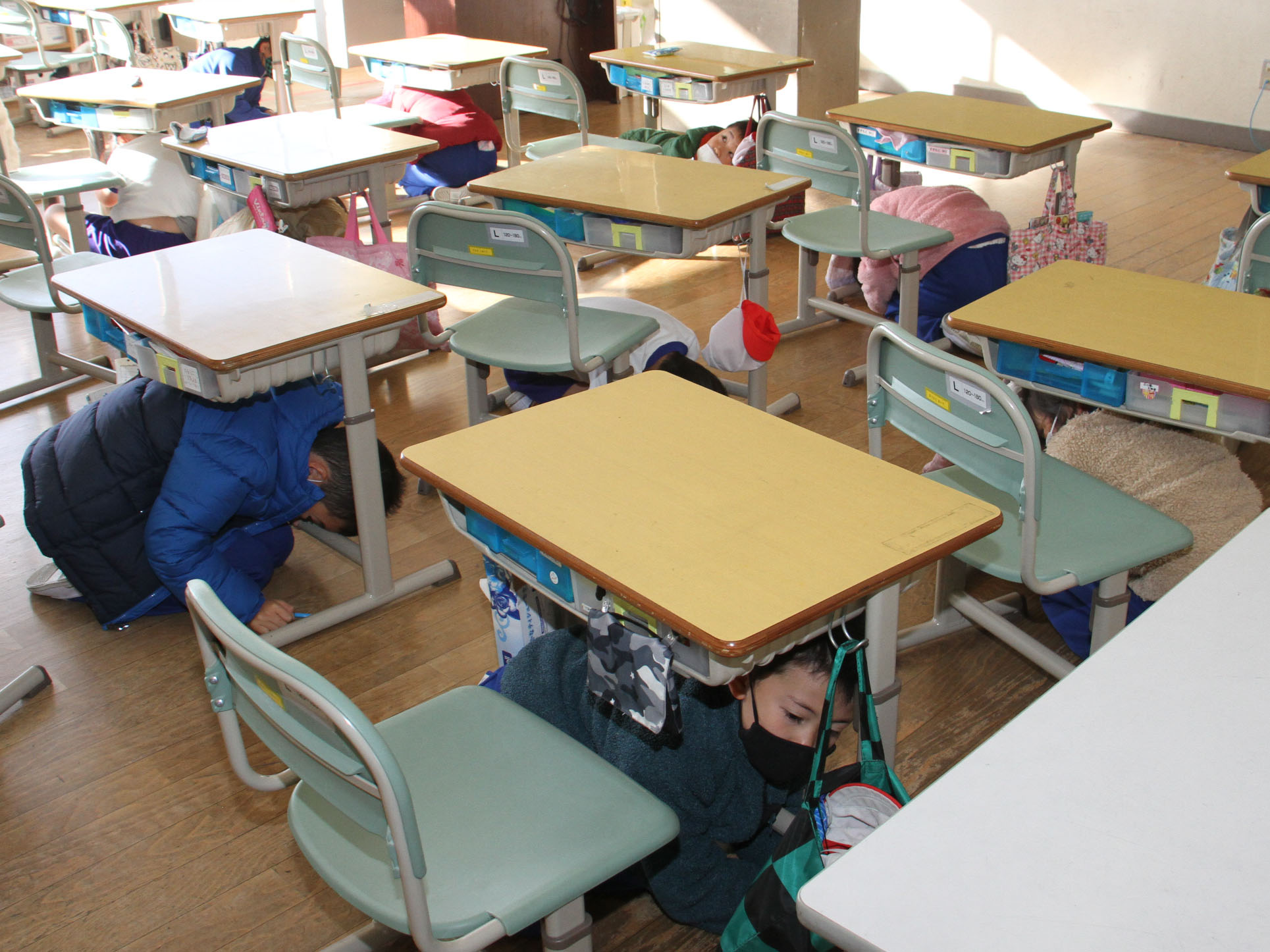 飯豊小学校避難訓練での机の下に隠れる様子