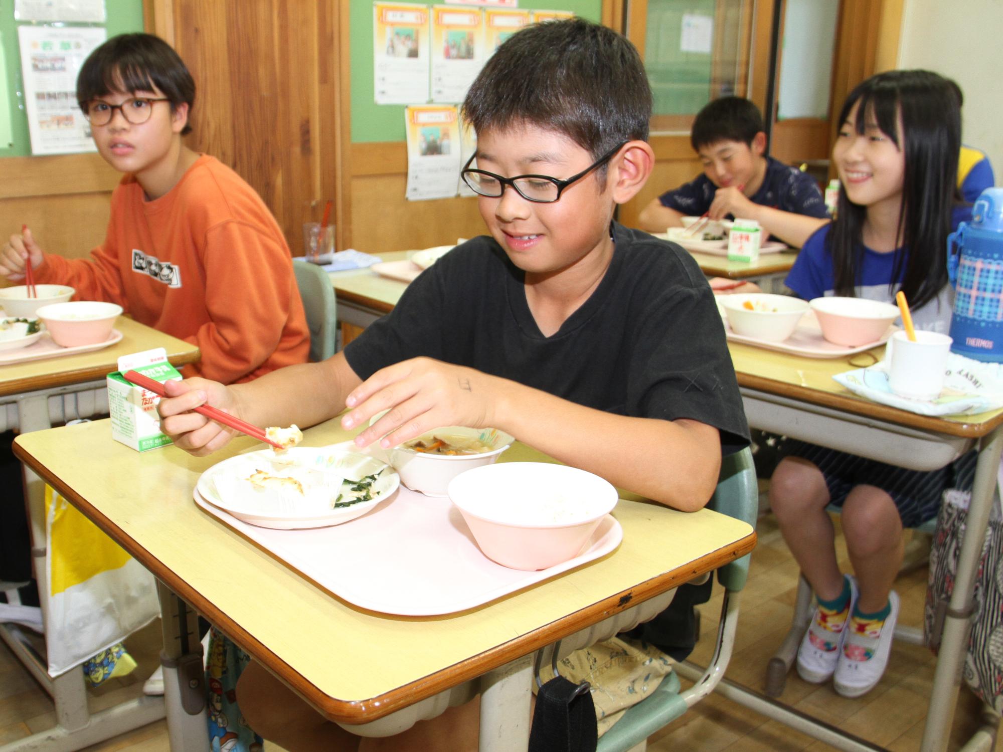 児童が給食でマダイのマヨネーズ焼きをおいしく食べる様子