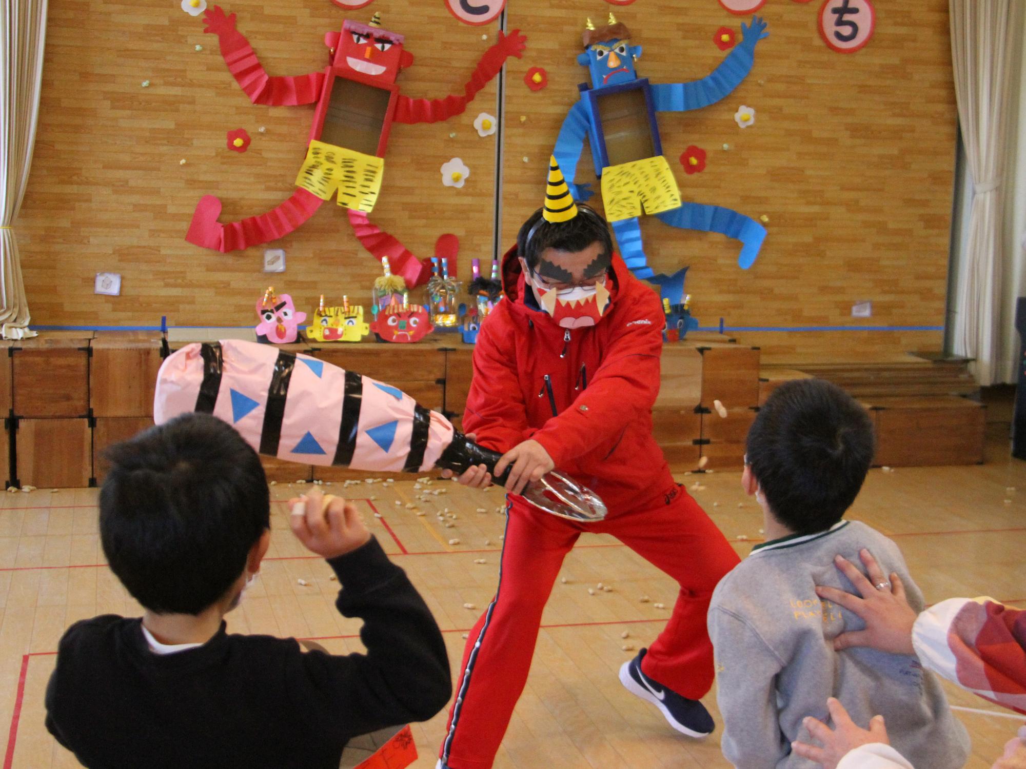 日立木幼稚園で赤鬼に扮した園長に豆まきをする園児らの様子