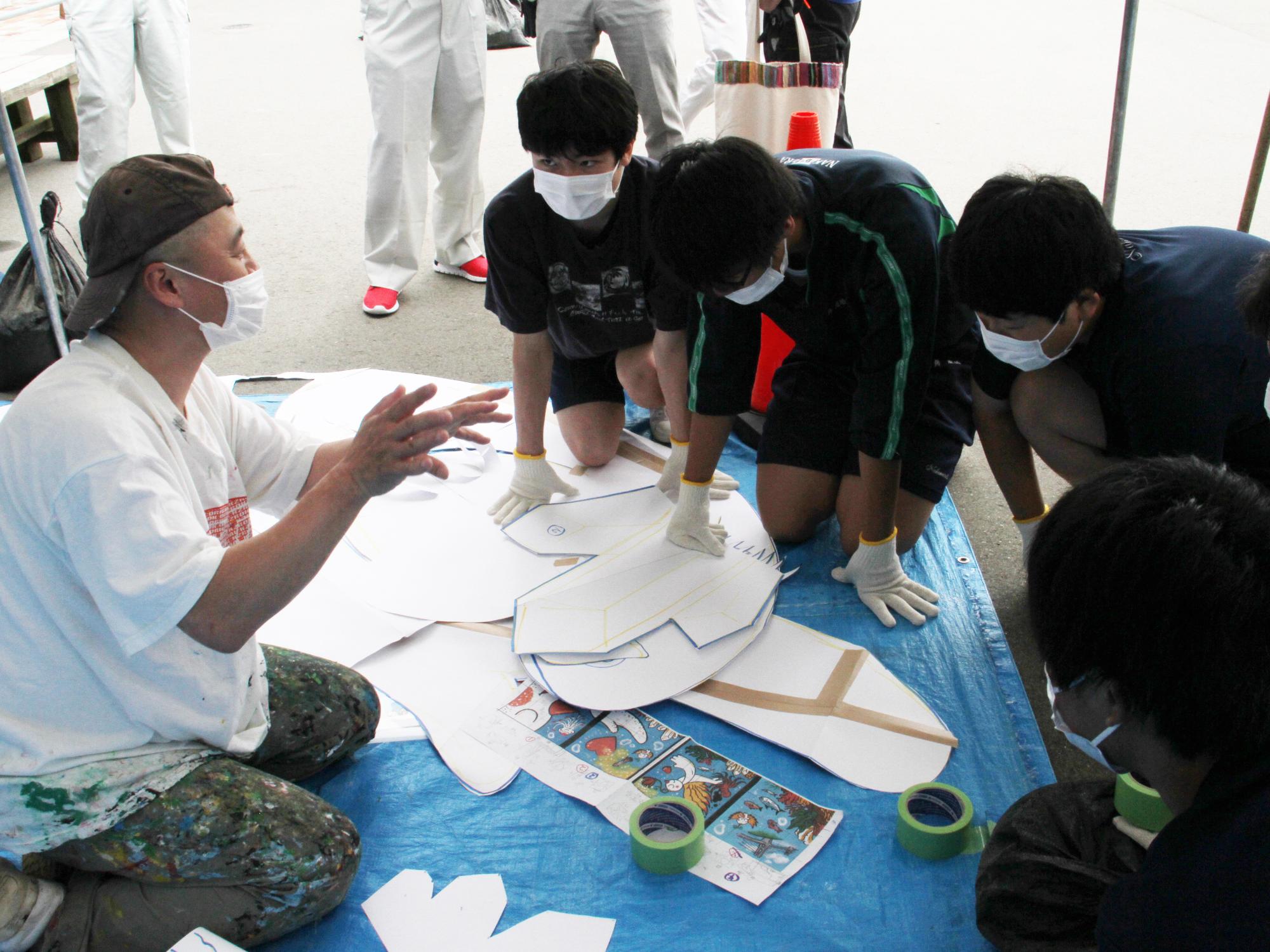 画家高岡洋介さんと中二中生が、安全通路の絵描きを行うため、作業の説明をしている様子