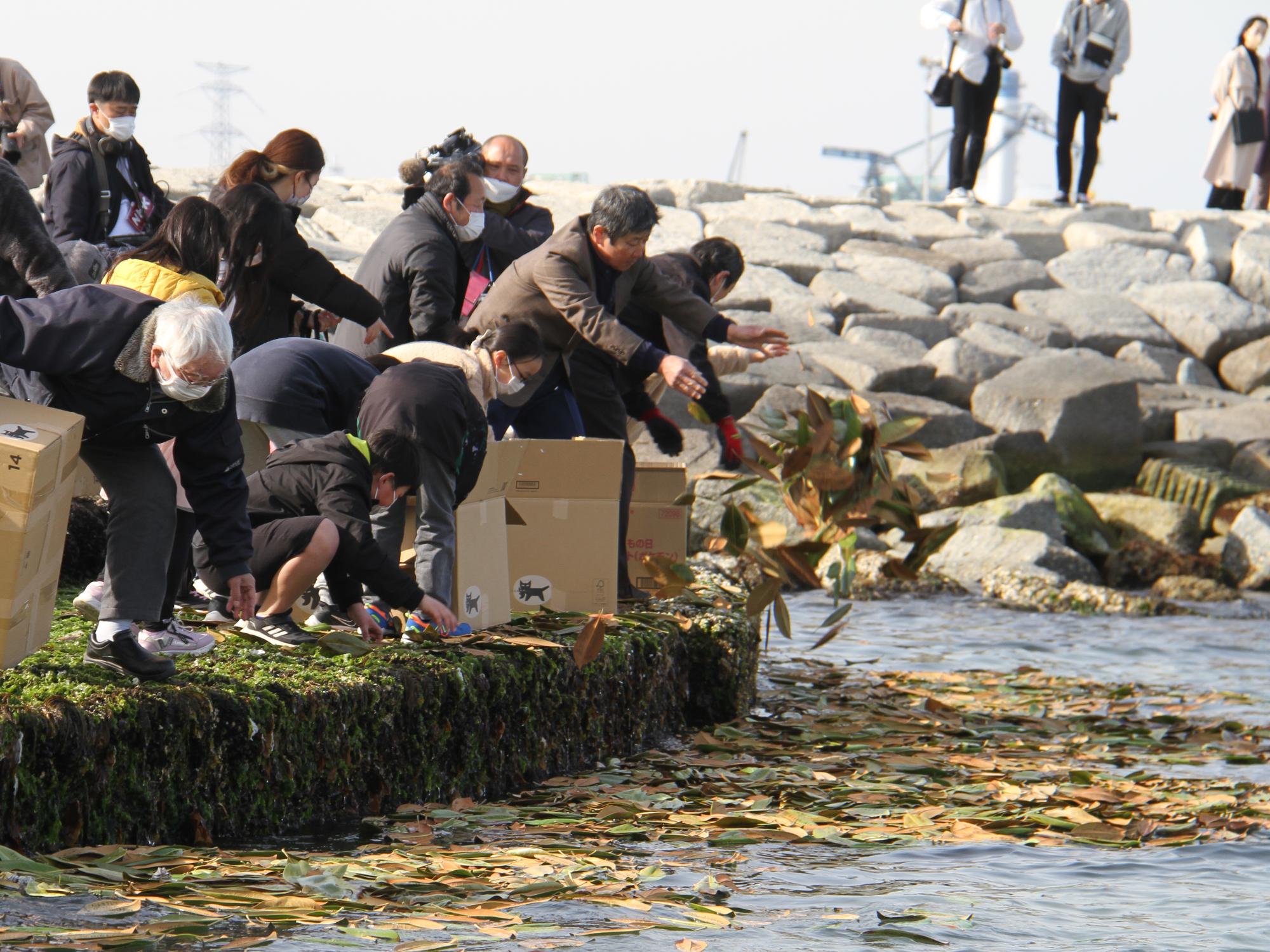 東日本大震災復興と鎮魂の集いで木の葉の船を海に流す様子