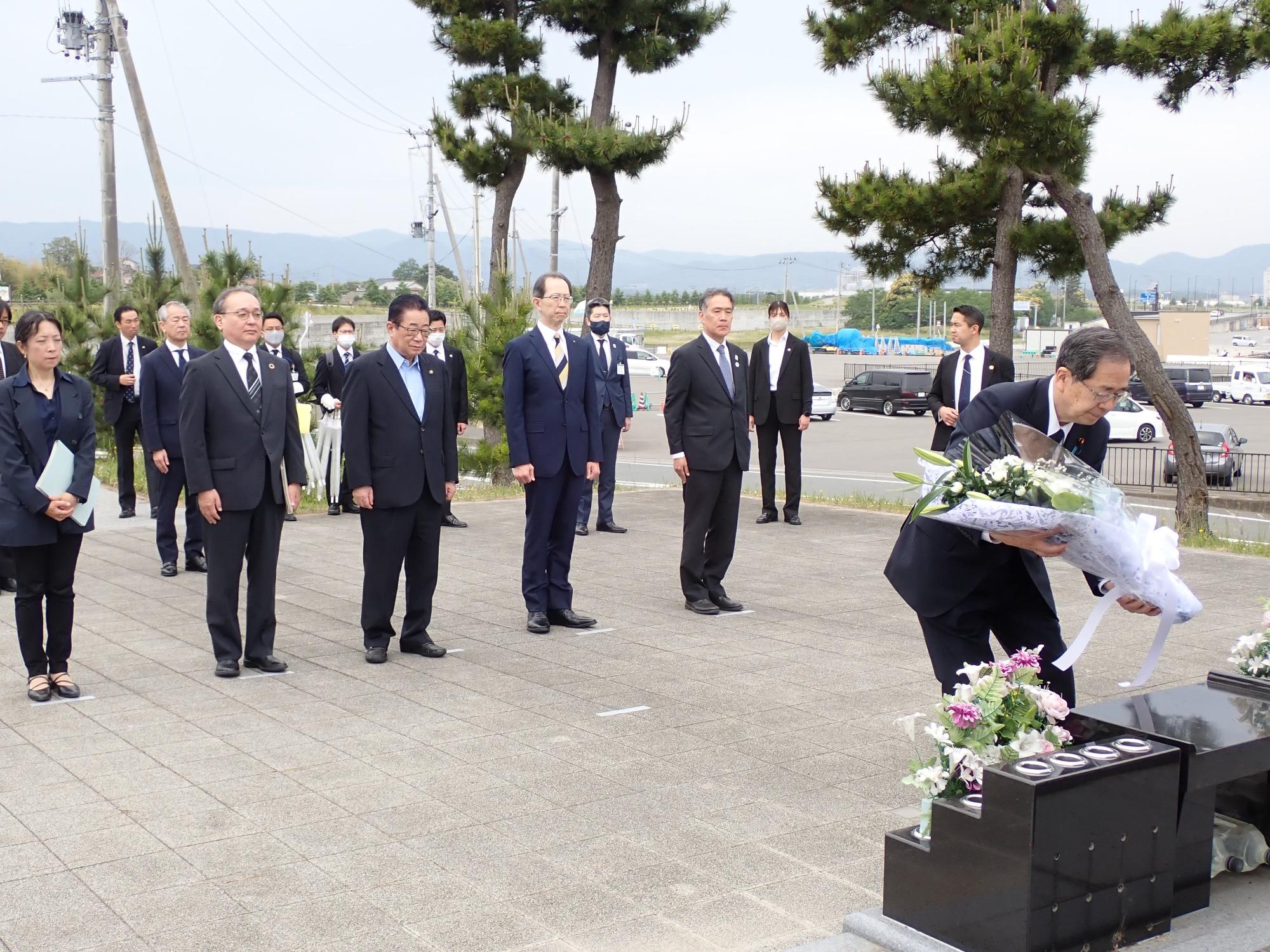 斉藤国交大臣らが東日本大震災慰霊碑（原釜地区）で花を手向け、黙とうする様子