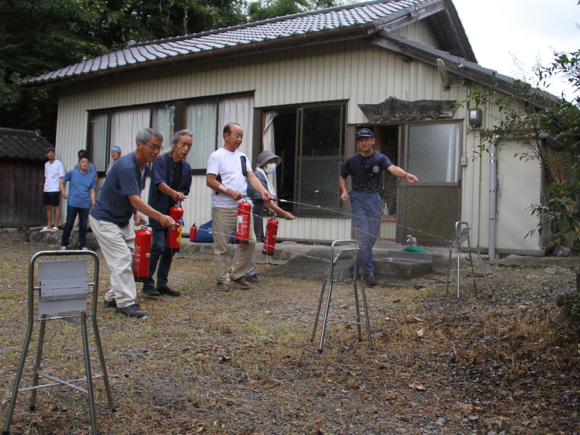 相馬消防署署員の指導のもと、水消火器を使用した初期消火訓練をする住民らの様子