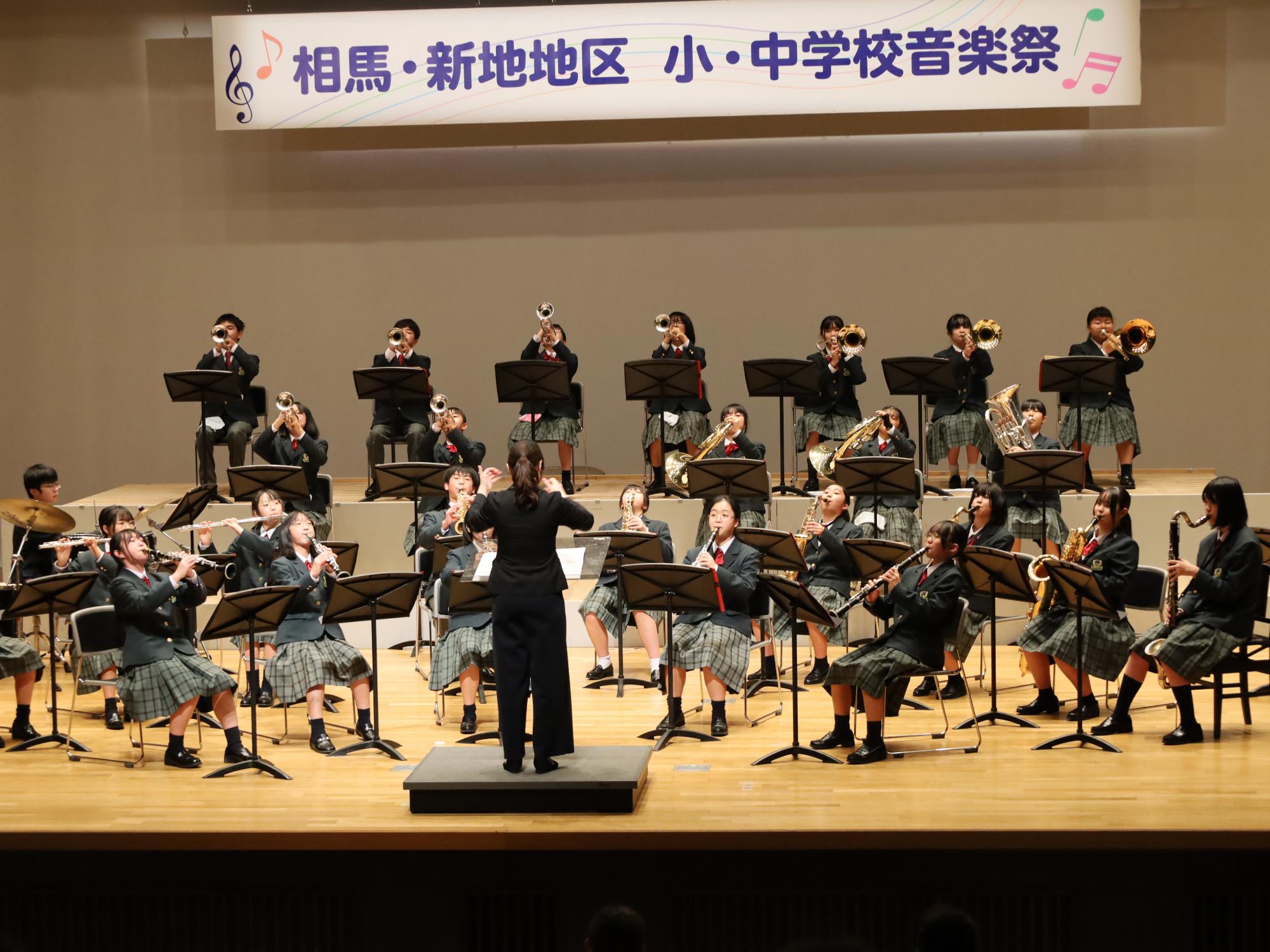 中村第一中学校の生徒らが市民会館大ホールステージで合奏する様子
