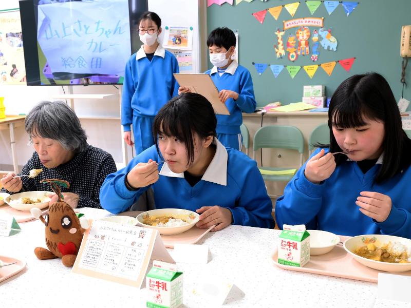 給食を食べる生徒と児童