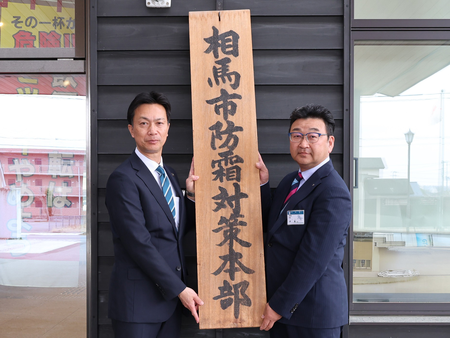 防霜対策本部の看板を掲げる市長と産業部長