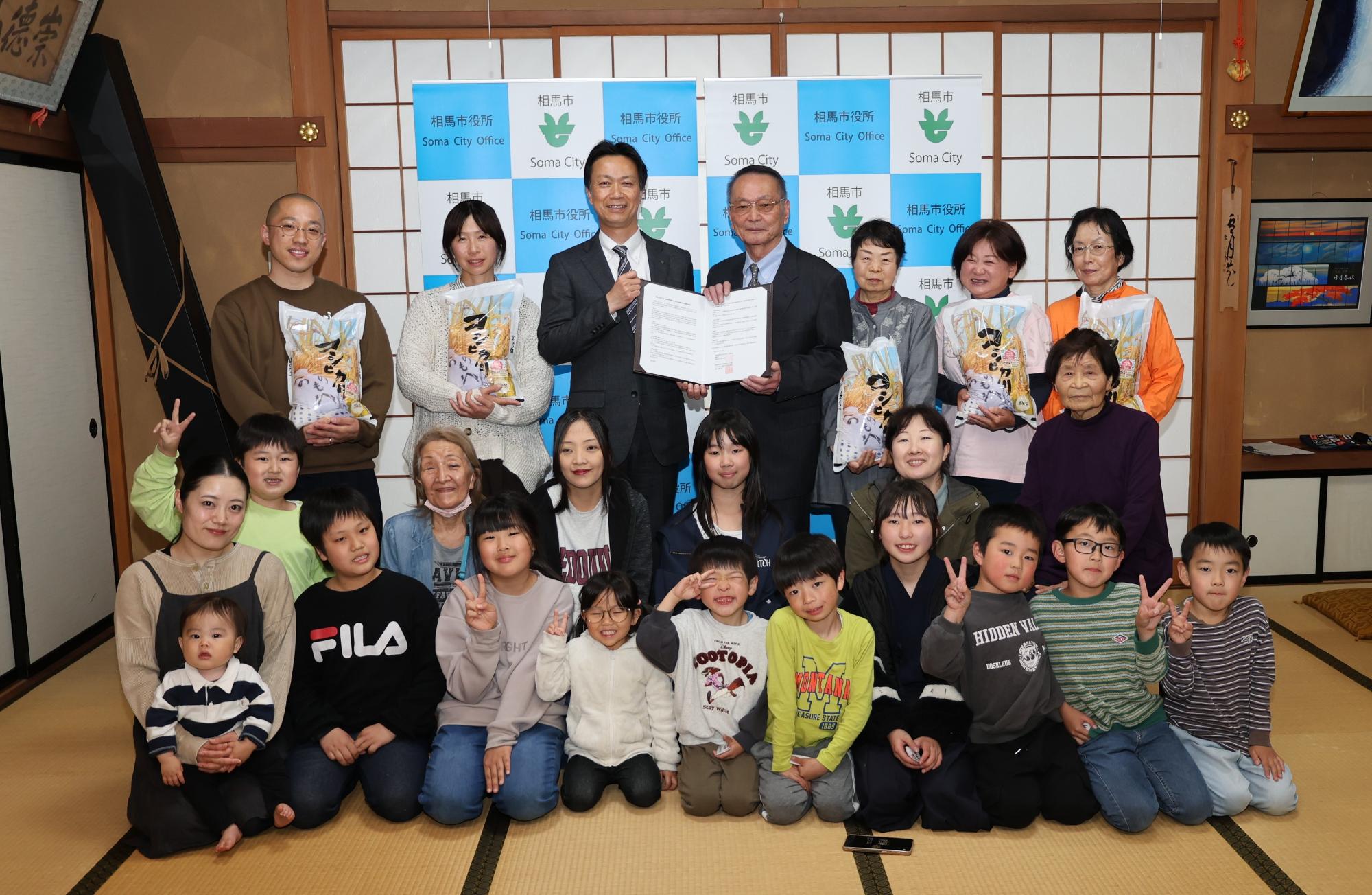 連携協定書を持つ阿部市長と只野社協会長、贈呈されたお米を持つ地域団体の5名、地域食堂に参加した方々